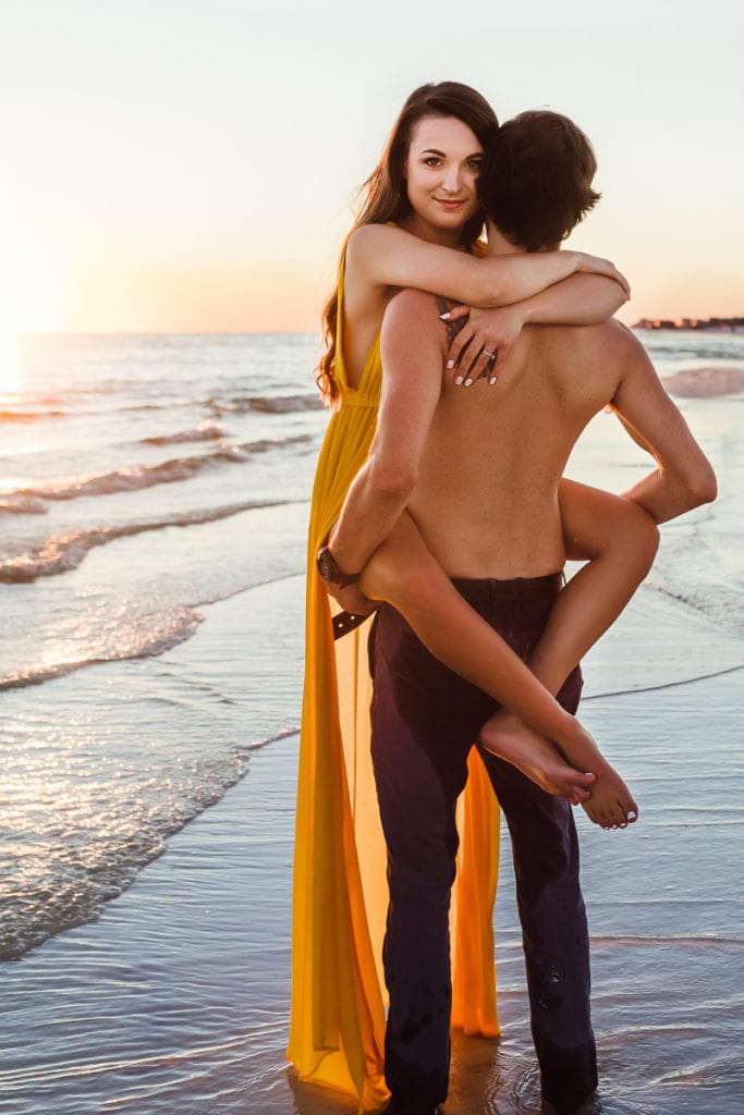 Family photographer, woman jumps into mans arms at the ocean